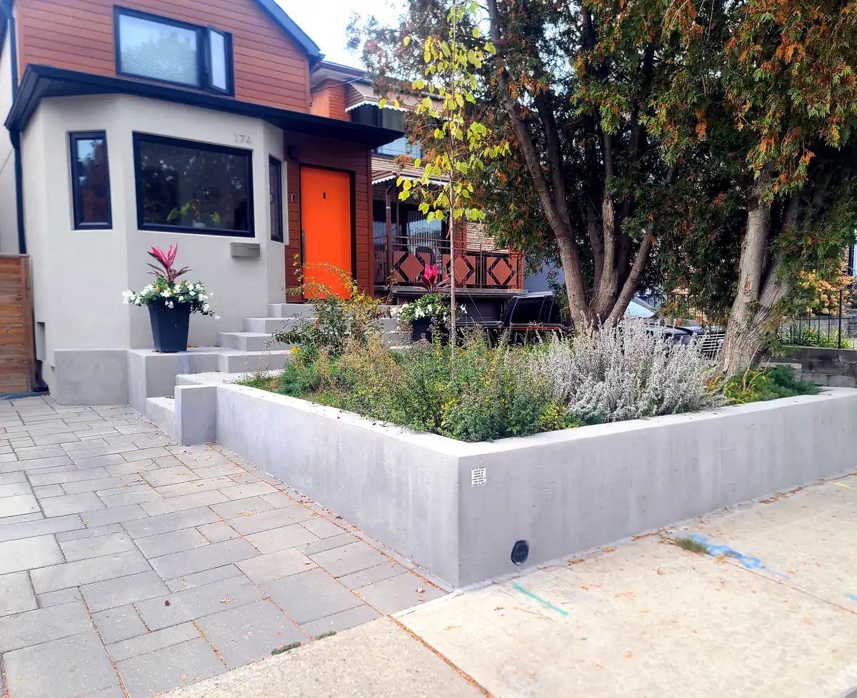 The same retaining wall finished, with a planted bed and a clean poured-concrete edge